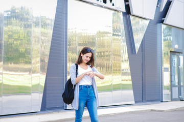 A young girl looks at a wristwatch outdoors. A teenager is watching time. Space for text.