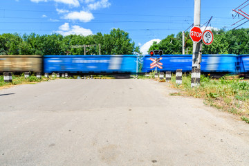 Fototapeta na wymiar Railroad crossing sign and blinking semaphore in front of the railroad crossing. Blurred motion of the train