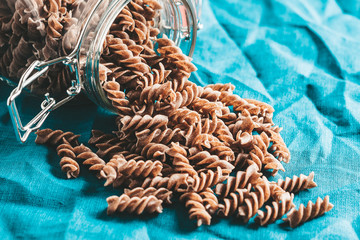 Dark brown pasta in a glass jar in the kitchen