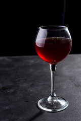 Red wine glass with long shadows on stone table. With copy space for your text