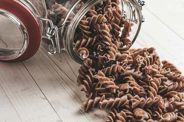 Tilted glass jar with pasta on the table