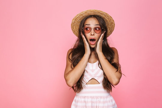 Photo of excited woman 20s wearing sunglasses and straw hat yelling at camera, isolated over pink background