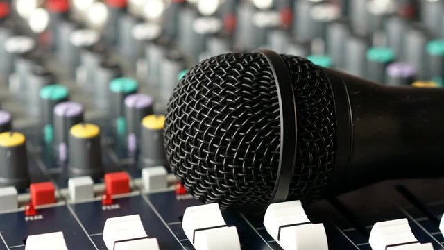 Dj puts microphone down on audio mixer console in music studio close up