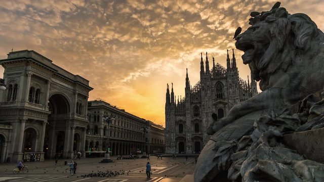 milano city center duomo square  cathedral with lion monument at dramatic cloudy sunrise with galleria Vittorio Emanuele 