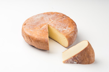 Top view of cheese wheel and slice on white.