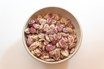 Ceramic bowl of red speckled October beans, centered, isolated on white, horizontal aspect