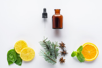 top view of bottle of natural herbal essential oil, dropper, fir, lemon and orange pieces isolated...