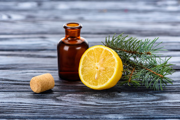 bottle of natural herbal essential oil, fir twigs, lemon and cork on surface
