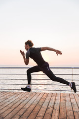 Handsome sports man outdoors on the beach running.