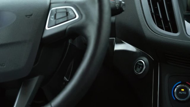 Close up of female finger pressing an engine start stop button in car