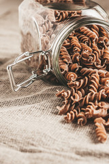 Wholegrain pasta with gluten in a glass jar in the kitchen