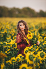 Obraz na płótnie Canvas Young beautiful woman in a dress among blooming sunflowers. Agro-culture.