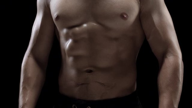 Man shows a muscular strong body close-up on a black background