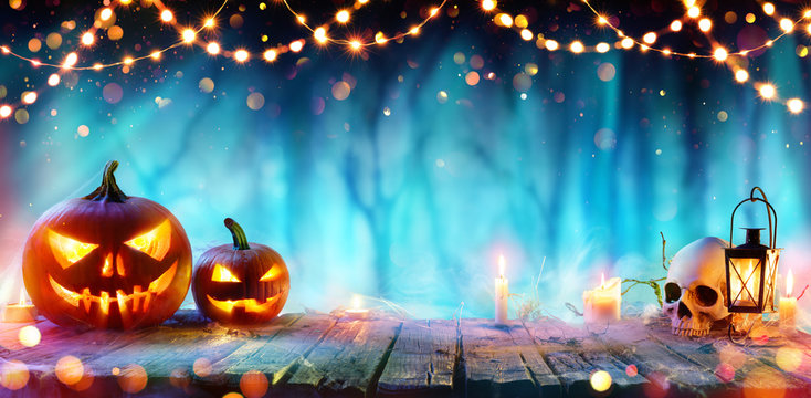 Halloween Party - Jack O' Lanterns And String Lights On Table In Misty Forest
