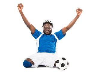 excited african american soccer player triumphing and smiling at camera isolated on white