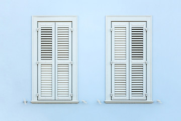 Two wooden retro style windows with shutters, on clean painted wall.