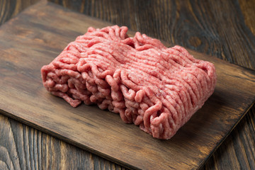 Raw minced meat in a plate on wooden background