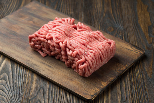 Raw minced meat in a plate on wooden background
