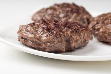 Homemade cutlets on a white plate and white background.