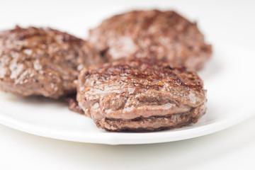 Homemade cutlets on a white plate and white background.