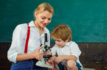 Lessons of science. Microscope. The teacher and student study biology at school. Friendly smiling teacher and pupil in classroom. Knowledge concept. Education. Teacher is warm accessible enthusiastic