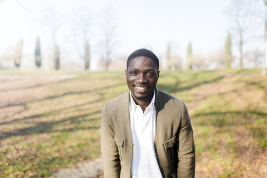 Portrait of young man in park, wearing jacket, smiling