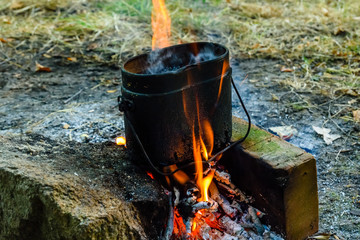 Cooking food in a kettle on bonfire