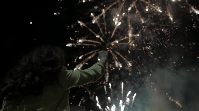 the girl at night looks at the fireworks in the sky. beautiful fireworks at night holiday lifestyle new year birthday. woman girl and fireworks concept night
