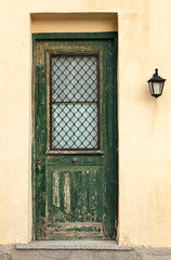 Old green wooden door with cracks, on weathered wall.