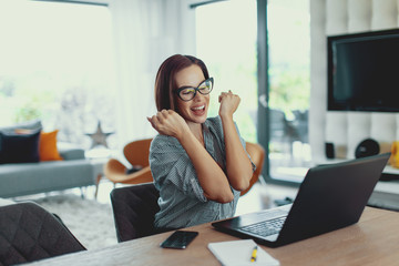 Young lucky succeessful freelancer woman in happiness at laptop