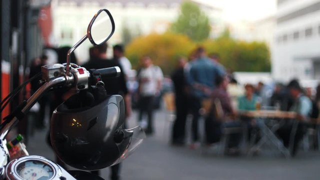 Motorcycle helmet hanging on the handles of the motorcycle hazy background with people