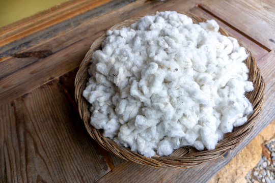 fluffy cottons or pudding, a raw material use for produce fabric, garment or cloth. Cottons in the bamboo basket put on wooden plank.