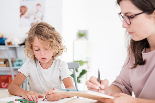 Child drawing pictures during meeting with therapist for orphan