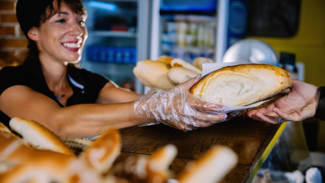 Smiling Female Bakery Assistant Gives Bread To The Customer