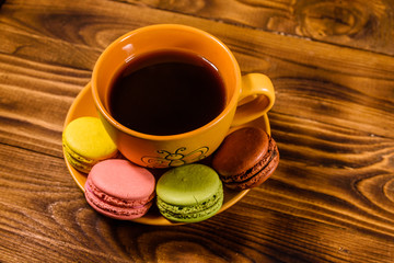 Cup of coffee and french macaroons on wooden table