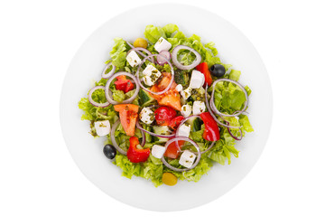 Greek salad with feta, olives, lettuce, red onion, cucumber, tomato, bell pepper, oil on plate, white isolated background, view from above, for the menu, restaurant bar cafe
