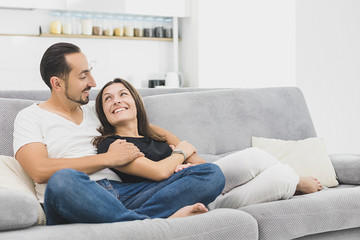 young woman with a young man resting on the couch. young woman with a young man looks at each other. side view