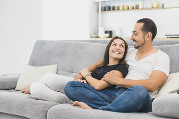 Loving couple on a new sofa are looking at each other. modern apartment. concept of comfort in a new apartment