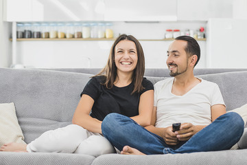 Happy couple sitting in a comfortable couch in the living room at home