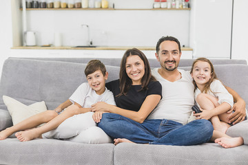 Happy family of four sitting on sofa. Happy family. Father, mother and children at home