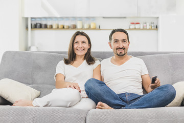 Smiling young couple relaxing and watching TV at home