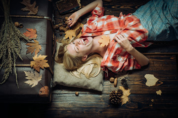 Fototapeta na wymiar Blonde girl lies on a warm blanket. Beautiful sexy young woman lies on wood background. Autumn happy people and joy. Black friday shopping. Autumn design.
