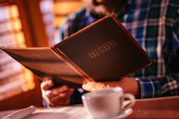 A Man Reading The Menu At A Classic Breakfast Diner