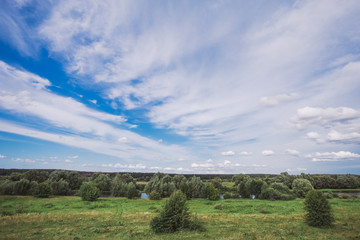 Fototapeta premium Beautiful green countryside landscape with charming calm blue sky with fluffy white clouds. Horizontal color photography.