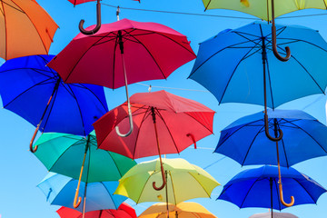 Fototapeta na wymiar Multicolored umbrellas on the city street. The city street is decorated with many colorful open umbrellas