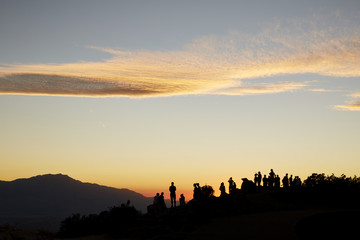 Silhouette of Large Crowd of Tourists on a Mountain Top at Sunset