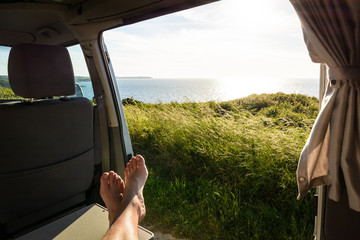 First-person view of a barefoot man relaxing inside a camper van and enjoying the view over the sea...