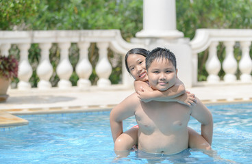 Fototapeta na wymiar Happy brother and sister play in swimming pool,