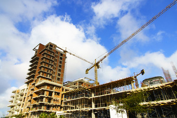 Naklejka premium Construction of a high-rise building with a crane. Building construction using formwork. The construction crane and the building against the blue sky.
