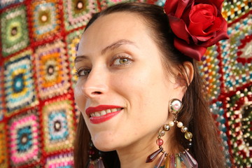 Beautiful gypsy woman in red with a red rose in her head on a bright background